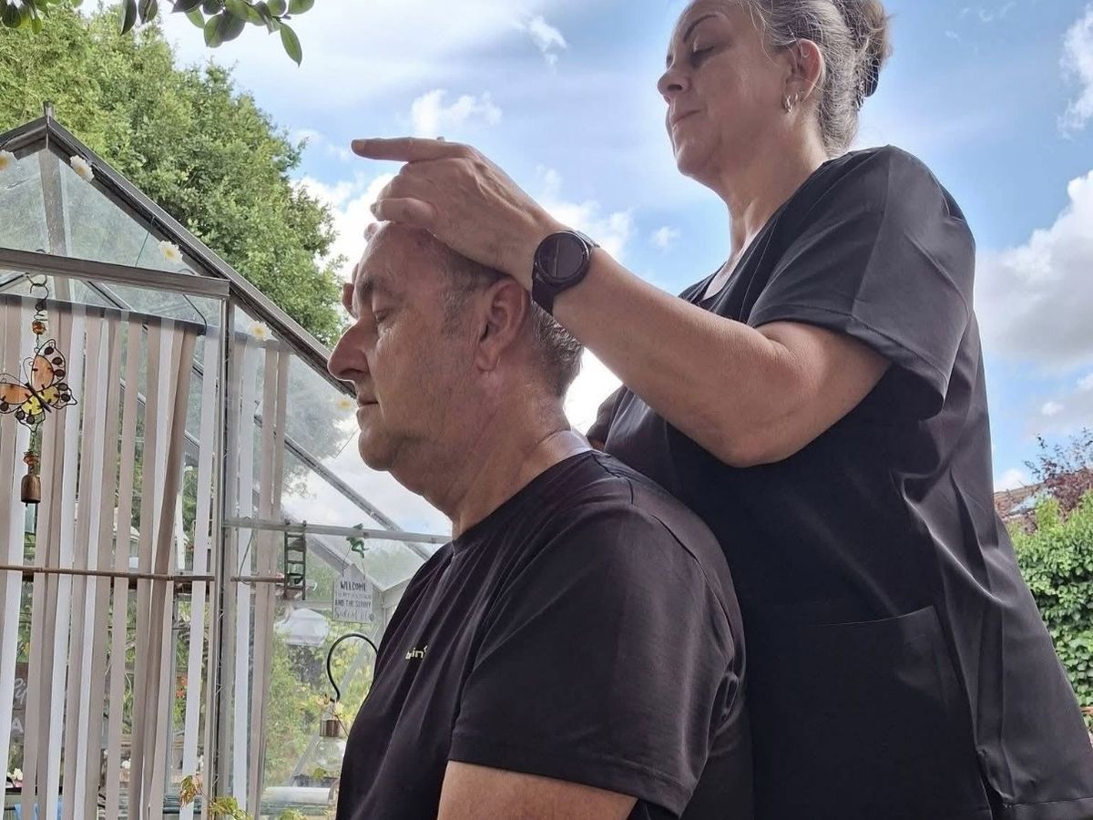 Indian Head Massage — Pauline working on a seated client's scalp and forehead in a garden